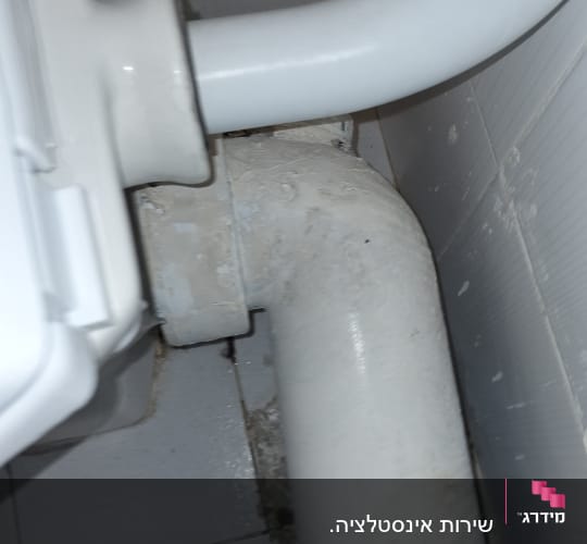 צינור ביוב לבן מחובר לקיר בחדר אמבטיה